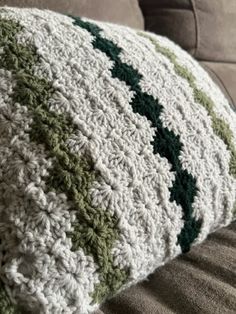 a green and white crocheted pillow on a couch