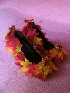 a pair of black high heeled shoes decorated with autumn leaves