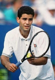 a man holding a tennis racquet on top of a tennis court with people in the background