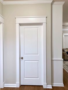 an empty room with a white door and wood flooring in it's center