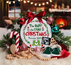 the baby who stole christmas sign surrounded by holiday decorations and toys in front of a fireplace