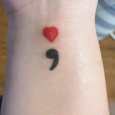 a small heart tattoo on the back of a woman's arm