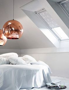 a bed with white sheets and pillows in a bedroom under a slanted skylight