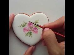 someone is painting a heart with flowers on it