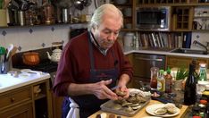 an older man in the kitchen preparing food on a plate and cutting it into small pieces