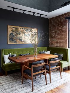 a dining room with a green couch and wooden table