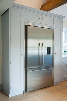 a stainless steel refrigerator and freezer combo in a large kitchen with white cabinetry