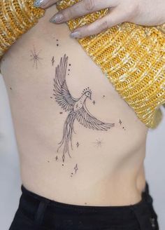 a woman's back with a bird tattoo on her stomach and stars in the background