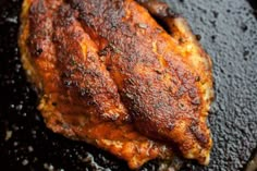 a piece of meat sitting on top of a black grilling pan covered in oil