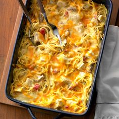 a casserole dish with noodles, meat and cheese in it on a wooden table