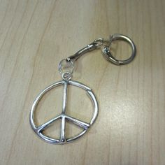 a peace sign keychain is shown on a wooden surface with a metal hook