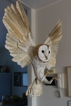 an owl made out of book pages hanging from the ceiling