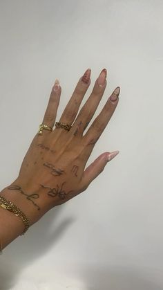 a woman's hand with tattoos on it and gold bracelets around her wrist