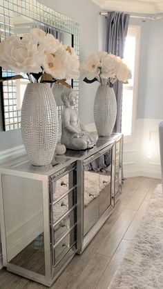 a living room filled with furniture and white flowers on top of a table in front of a mirror