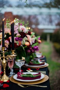 the table is set with black and gold plates, red napkins, and candles