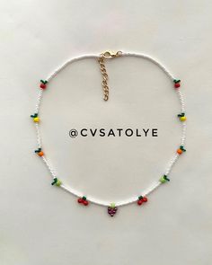 a white beaded bracelet with colorful beads and charms on the clasp that says cvvsatolye