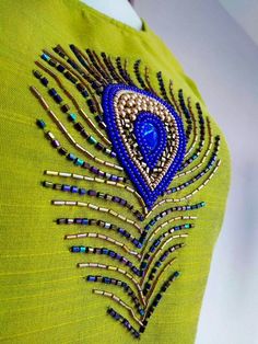 a green dress with blue and gold beading on the back, featuring a peacock's tail