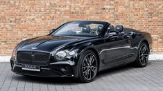 a black convertible car parked in front of a brick wall