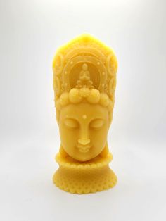 a yellow buddha statue sitting on top of a white surface