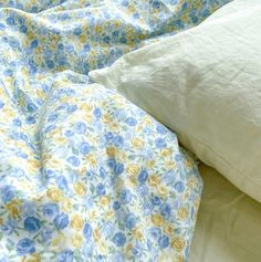 an unmade bed with blue and yellow flowers on it