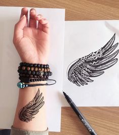 a woman's arm with two bracelets on it and an ink drawing of a wing