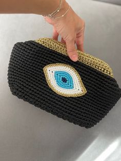 a woman's hand holding a black purse with an eye on it