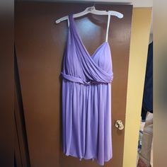 a purple dress hanging on a hanger next to a door