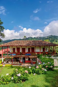 an old house with red and white trim on the roof is surrounded by lush greenery