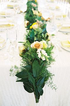 a long table with flowers and greenery on it