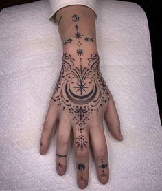 a woman's hand with tattoos on it sitting on top of a white sheet