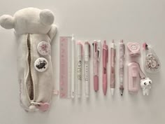 several pens, pencils, and stuffed animals are lined up on a white surface