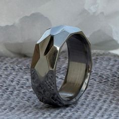 a silver ring sitting on top of a piece of cloth next to snow covered ground