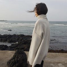 a woman standing on the edge of a cliff looking out at the ocean