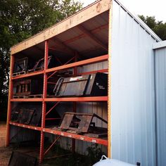 an old metal storage shed with lots of junk on it's sides and several other items stacked up in the back