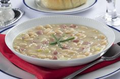 a white bowl filled with soup on top of a red napkin next to silverware