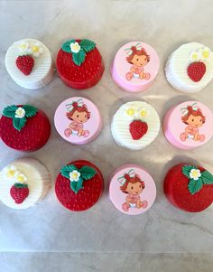 twelve strawberry shortcakes are arranged on a marble counter top with white frosting and red icing