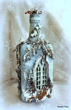 a bottle with a house on it is covered in snowflakes and pine cones