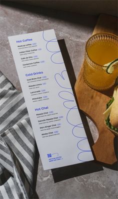 a menu sitting on top of a wooden cutting board next to a glass of orange juice