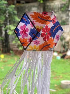 a close up of a colorful kite with flowers on it's sides and fringes