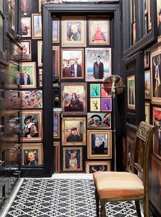 a room with many framed pictures on the wall and a chair in front of it