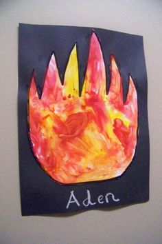 a child's handprinted fire on a black piece of paper with the word aden written in white