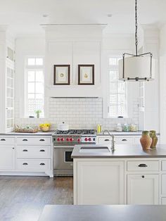 a kitchen with white cabinets and an island in front of the stove top is surrounded by wood flooring