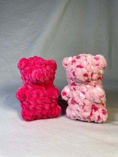 two pink and one red teddy bears sitting next to each other on a white background