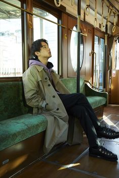 a man in a trench coat sitting on a train