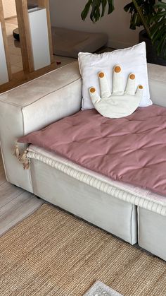 a white couch with pillows on it in front of a potted plant and rug