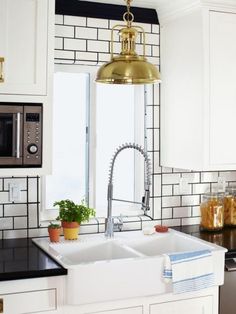 a kitchen with white cabinets, black counter tops and a gold faucet hanging over the sink