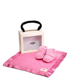 a pair of pink slippers sitting on top of a blanket next to a box