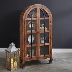 a wooden display case sitting next to a small lantern on top of a cement floor