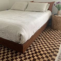 a bed sitting on top of a brown and white rug