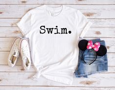 a white shirt with the word swim on it next to a pair of denim shorts